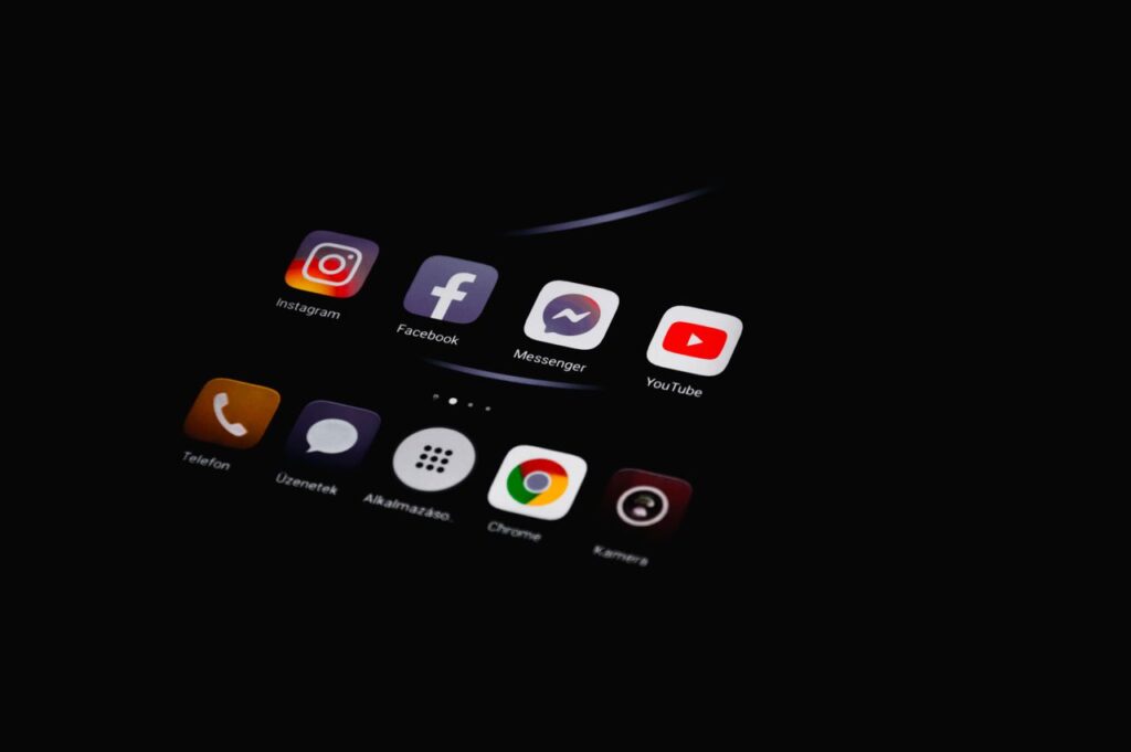 Close-up of smartphone displaying popular social media apps in dim lighting.
